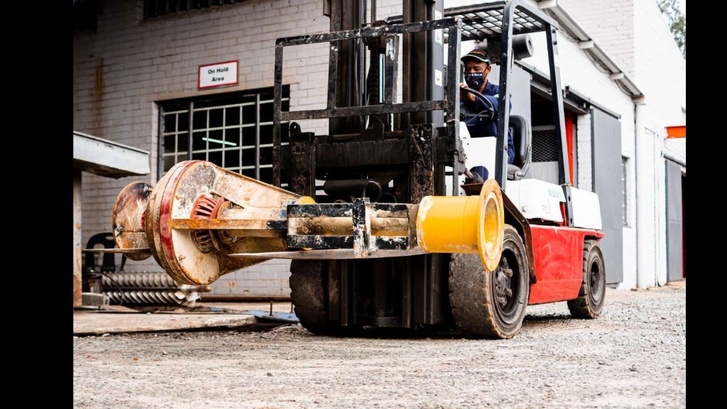 Forklift operator moving a heavy industrial pump assembly outside the Titan Pumps workshop
